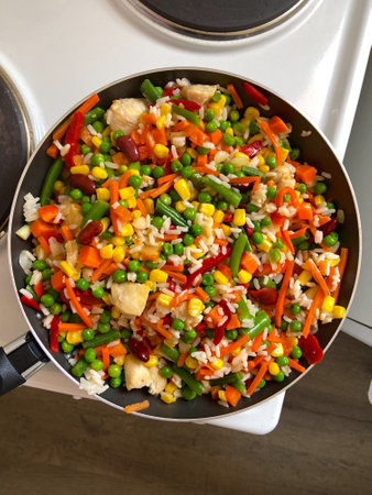 Vibrant stir-fry of colorful vegetables and rice in a pan creates a lively and delicious visual feast. The dishs bright hues and variety of ingredients highlight the joy and creativity of cooking at homeの写真素材