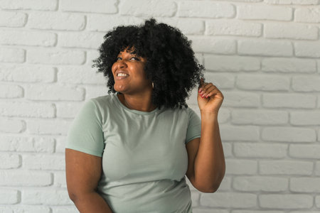 African American confident woman playfully showcasing her natural hair with a humorous expression, copy space. Conveys self-love, personality and an appreciation for individuality.の写真素材