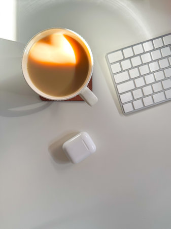 Cup of coffee with a heart-shaped reflection for Valentines day, placed on a clean white desk. Soft...