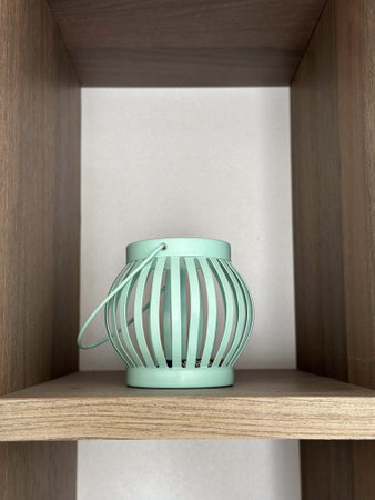 A mint green lantern on a minimalist wooden shelf. Elegant accessory adds a touch of charm to modern interior designsの写真素材