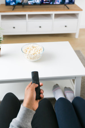 Remote control is pointed toward the television screen, control and choice of tv entertainment. TV, series and streaming service conceptの写真素材