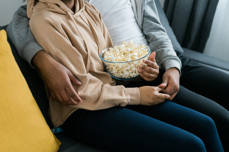Close up of hands taking popcorn from bowl.の写真素材