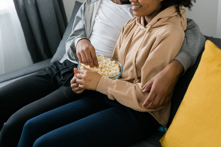 Close up of hands taking popcorn from bowl.の写真素材