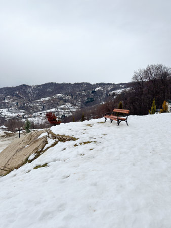 Bench covered with snow in frozen day. Empty bench in snowy park. Winter weather. Wooden bench in...