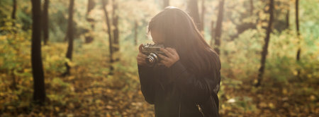 Banner Child girl using an old-fashioned camera in autumn nature copy space. Photographer, fall season and leisure concept.の写真素材