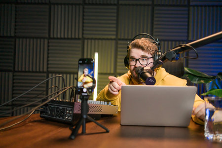 Young smiling male radio presenter talking into the microphone and reading news, information and communication concept. Podcast and internet streaming concept.の写真素材