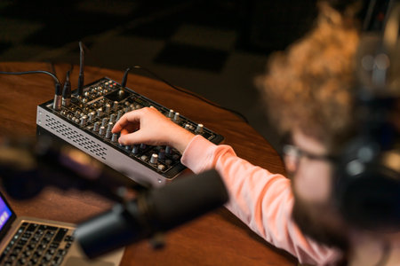 Cheerful young man recording podcast in studio. Confident man with headphones and microphone recording a podcast. Happy guy talking on web radio.の写真素材