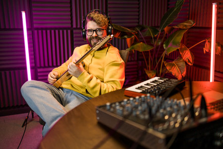 Man vocal artist singing in a recording studio with guitar. Male singer singing a song and playing...