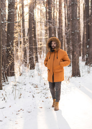 Man walking along snowy path in winter forest. Mindfulness, seasonal change, and harmony with nature during a peaceful outdoor moment.の写真素材