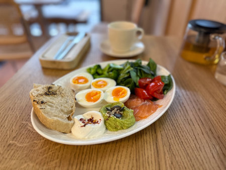 Balanced breakfast with eggs, salmon and vegetables on wooden table. Healthy eating, mindful routine and morning energy boostの写真素材