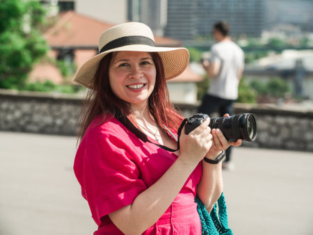 Smiling woman using a camera to take photo outdoors at the park.