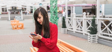 Banner woman checks phone after shopping in the city, copy space. Modern habits of reviewing shopping experiences onlineの写真素材