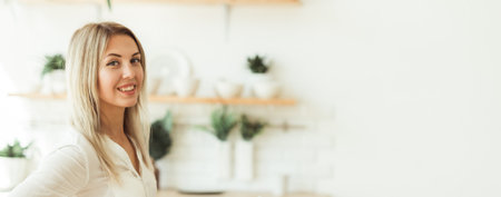 Portrait of a smiling woman standing at home. Positive attitude and modern lifestyle concept. Banner with copy spaceの写真素材