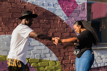 African american couple dancing together outdoors near colorful wall. Concept of love, joy, movement...
