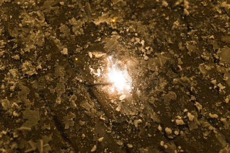Sparkler burns on winter pavement. Concept of celebration, magic, fleeting moment in urban setting