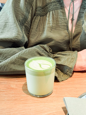 Green matcha latte close-up on wooden table. Drinks, modern lifestyle and coffee shop concept