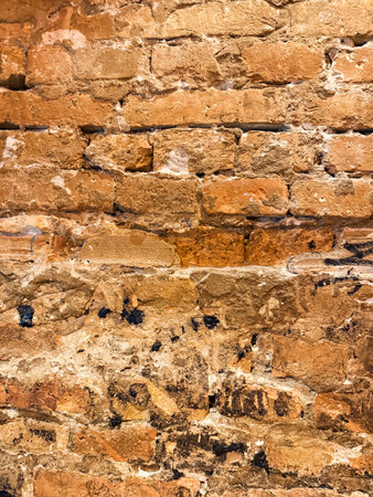 Weathered red brick wall with vintage patina and grunge texture. Warm tones and aged surface enhance...