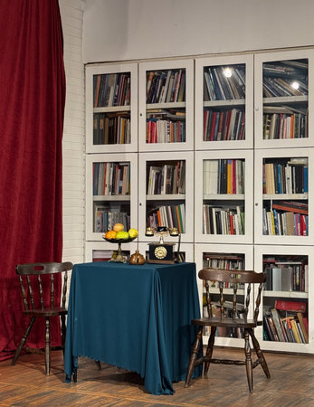 Vintage library corner with antique phone, wooden chairs and bookshelves. Cozy retro space for...