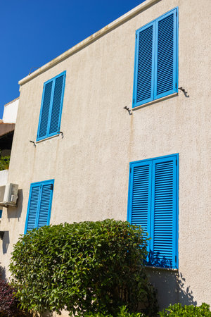 Facade with closed blue shutters. Mediterranean architecture, sunny climate, and summer lifestyle in coastal residential buildingsの写真素材