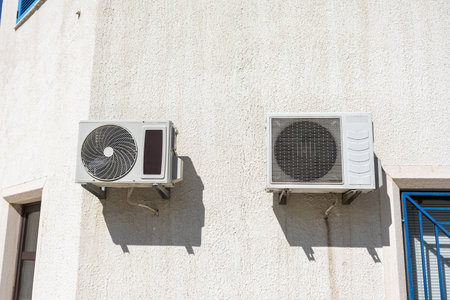 Two air conditioning units on facade. Climate control, summer infrastructure, and residential cooling in urban housing.の写真素材