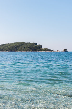 Island in blue sea with clear water. Summer seascape, natural tranquility, and peaceful horizon in...