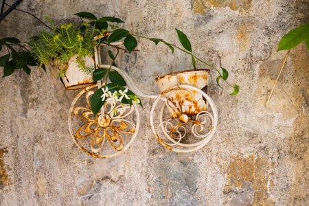 Rusty flower pot bicycle decor against textured stone wall. Vintage charm, creative gardening, and rustic outdoor detail.の写真素材