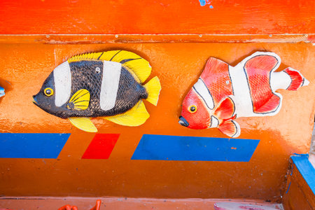 Colorful fish decorations on painted surface. Marine theme, children attraction, and playful coastal design.の写真素材