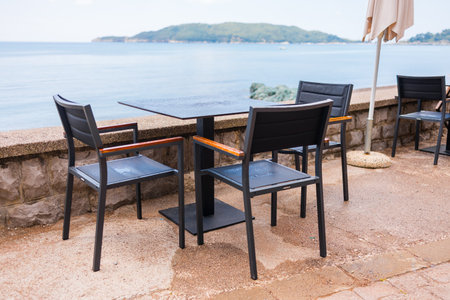 Outdoor cafe or restaurant with sea view and empty chairs. Coastal relaxation, summer tourism, and beachfront dining in the Mediterranean region.の写真素材