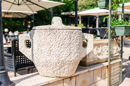Rough stone trash bin with lid in outdoor cafe. Rustic design, urban furniture, and Mediterranean architectural detail.の写真素材