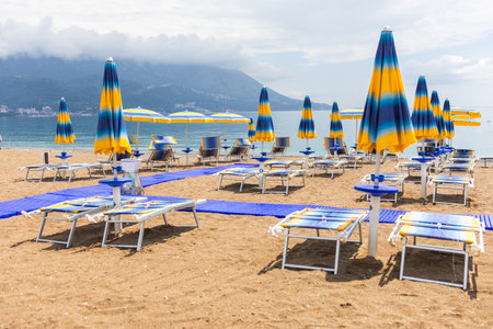 Tranquil morning at a beach with blue umbrellas and loungers. Coastal vacation, summer relaxation and peaceful seaside tourism.の写真素材