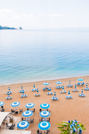 Tranquil morning at a beach with blue umbrellas and loungers. Coastal vacation, summer relaxation and peaceful seaside tourism.の写真素材