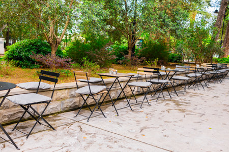 Outdoor cafe seating in leafy park setting. Relaxed urban lifestyle and social gathering space surrounded by greenery.の写真素材