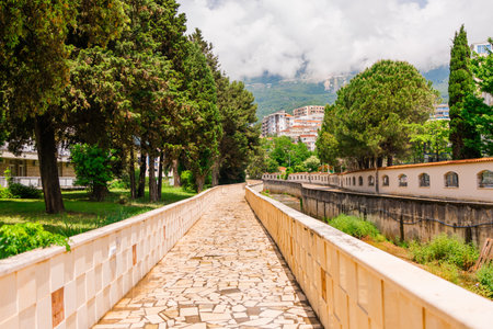 Scenic walkway in Budva with stone pavement and cypress trees. Urban nature, peaceful atmosphere and summer strolls in Montenegro.の写真素材
