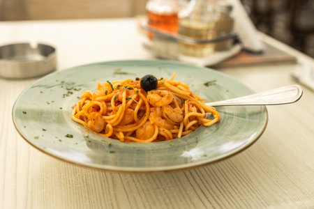 Shrimp spaghetti with tomato sauce served on ceramic plate. Mediterranean cuisine, seafood lunch and Italian restaurant dining.の写真素材