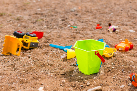 Children beach toys scattered on sand near the shoreline. Childhood, summer vacation and carefree playtime by the sea.の写真素材
