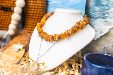 Amber necklace on white stand with seashell pendant. Natural gemstone, coastal aesthetic, and handcrafted summer accessory for beach inspired fashion.の写真素材
