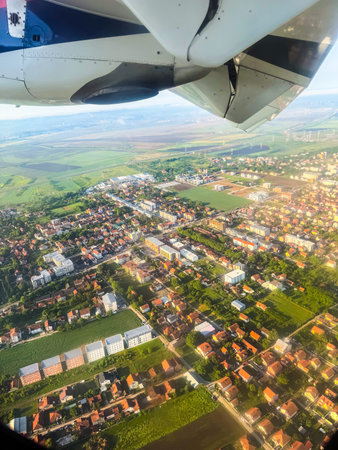 Aerial view of town and countryside from airplane window with engine visible. Urban planning, landscape diversity, and in-flight travel perspective.の写真素材
