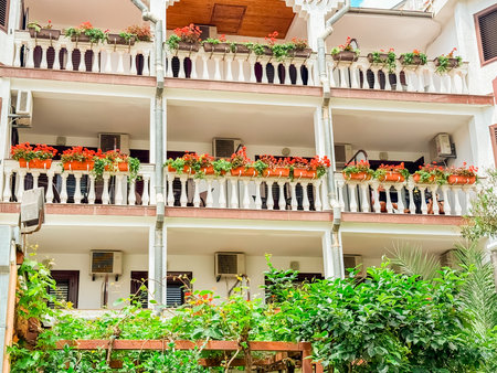Balconies decorated with red flowers and green plants. Architecture, lifestyle, tradition and atmosphere in an urban residential building.の写真素材