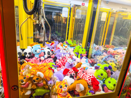 Claw machine filled with colorful stuffed animals and toys. Entertainment, leisure, childhood and amusement in an indoor arcade setting.の写真素材