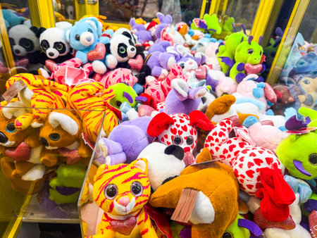 Claw machine filled with colorful stuffed animals and toys. Entertainment, leisure, childhood and amusement in an indoor arcade setting.の写真素材