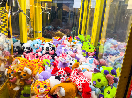 Claw machine filled with colorful stuffed animals and toys. Entertainment, leisure, childhood and amusement in an indoor arcade setting.の写真素材