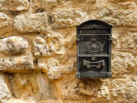 Vintage mailbox with emblem mounted on a stone wall with copy space. Communication, tradition, history and culture in an urban architectural setting.の写真素材