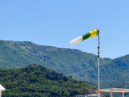A windsock fluttering in the wind against a mountain background. Measurement, weather observation and connection to natural air currents.の写真素材