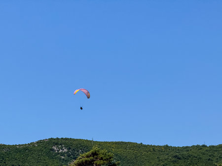 A paraglider flying high in the clear blue sky above the horizon. Freedom, adventure and extreme recreation in open aerial space.の写真素材