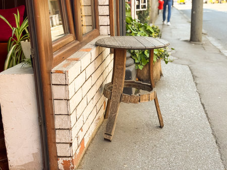 Weathered wooden table placed by the wall of a street cafe. Rustic charm, nostalgia and everyday urban simplicity.の写真素材