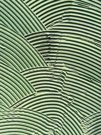 Textured wall surface with layered patterns in green color. Abstract design, geometric rhythm and creative urban detail.の写真素材