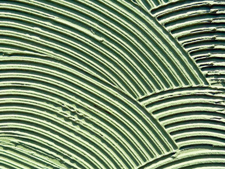 Textured wall surface with layered circular patterns in green color. Abstract design, geometric rhythm and creative urban detail. Copy spaceの写真素材