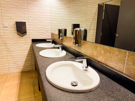 Triple sink counter with mirror and tiled wall in modern restroom. Cleanliness, hygiene, and...