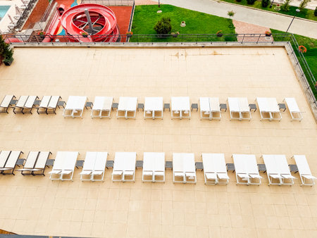 Rows of outdoor loungers arranged in geometric alignment on resort terrace with clear pattern. Tourism, leisure, and hospitality symbolizing relaxation, vacation lifestyle, and modern recreation.の写真素材