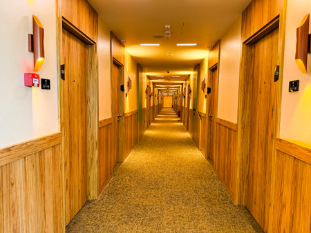 Hotel corridor with wooden panels and warm lighting leading to guest rooms. Interior design, hospitality, and tourism symbolizing relaxation, architecture, and modern comfort.の写真素材